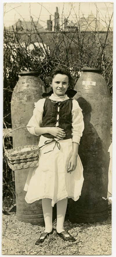 Young Girl in Front of Two Large Artillery Shells Holding a Basket by Carl Michel